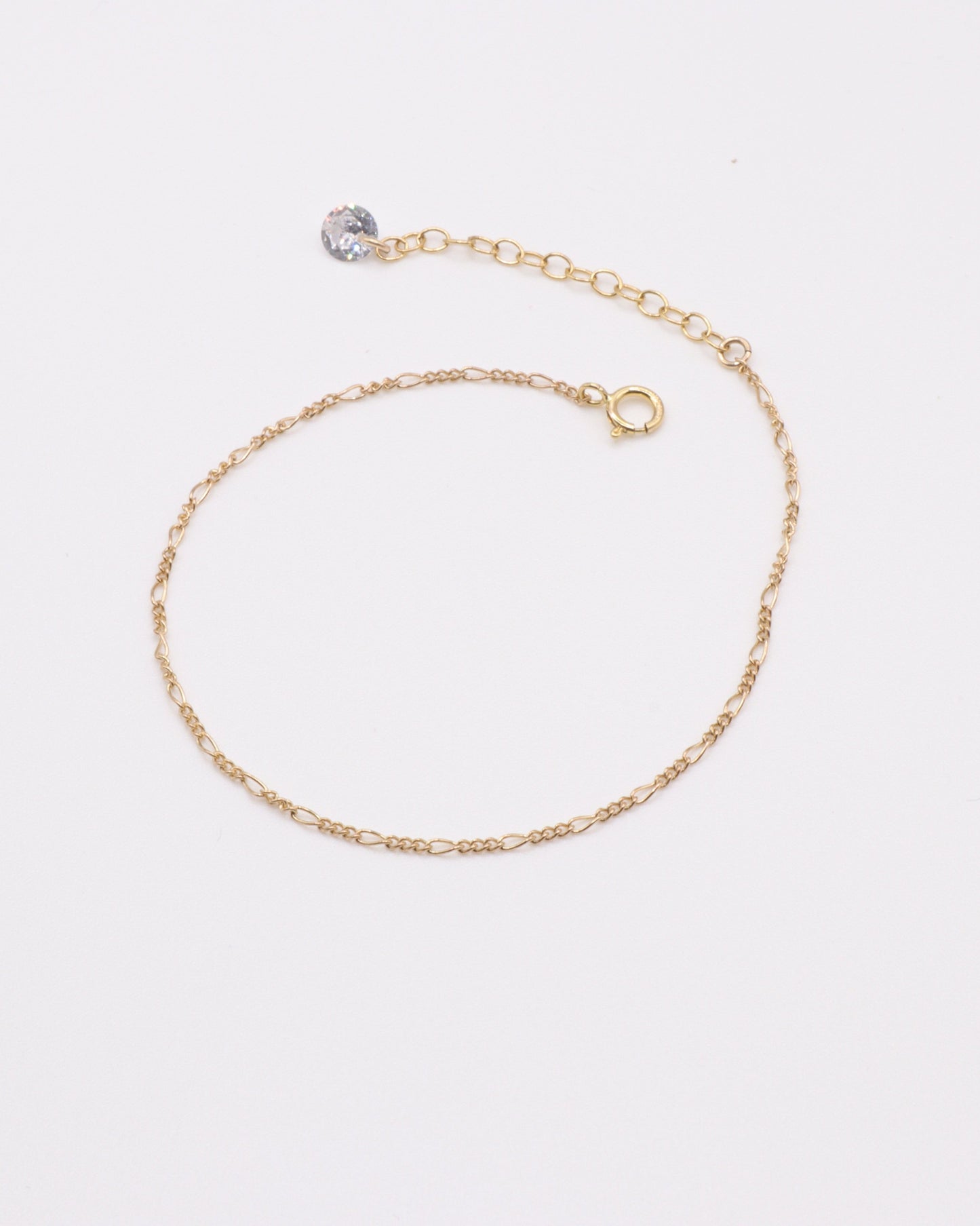 Photo du bracelet figaro et zirconium en acier inoxydable doré à l'or 750/1000ème (18 carats) sur fond gris clair