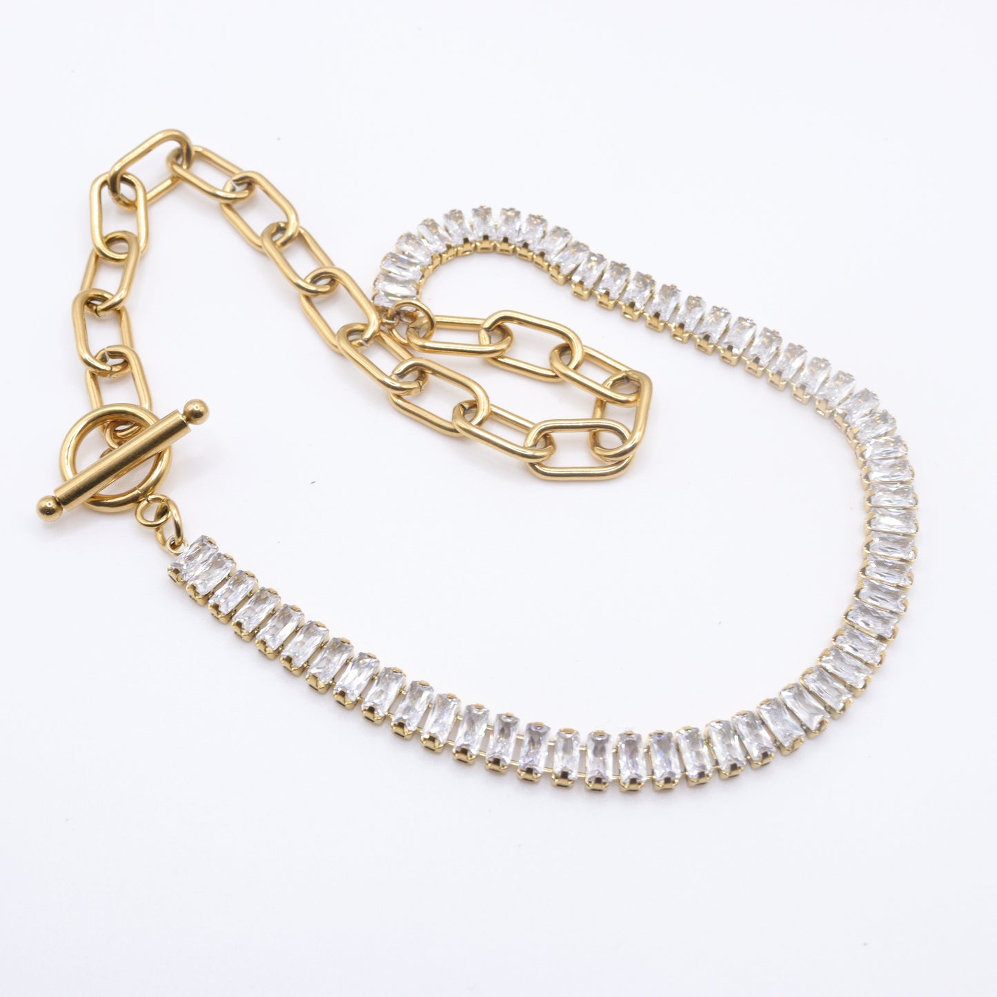 Photo du collier tennis et trombone en acier inoxydable doré à l'or 750/1000ème (18 carats) sur fond gris clair