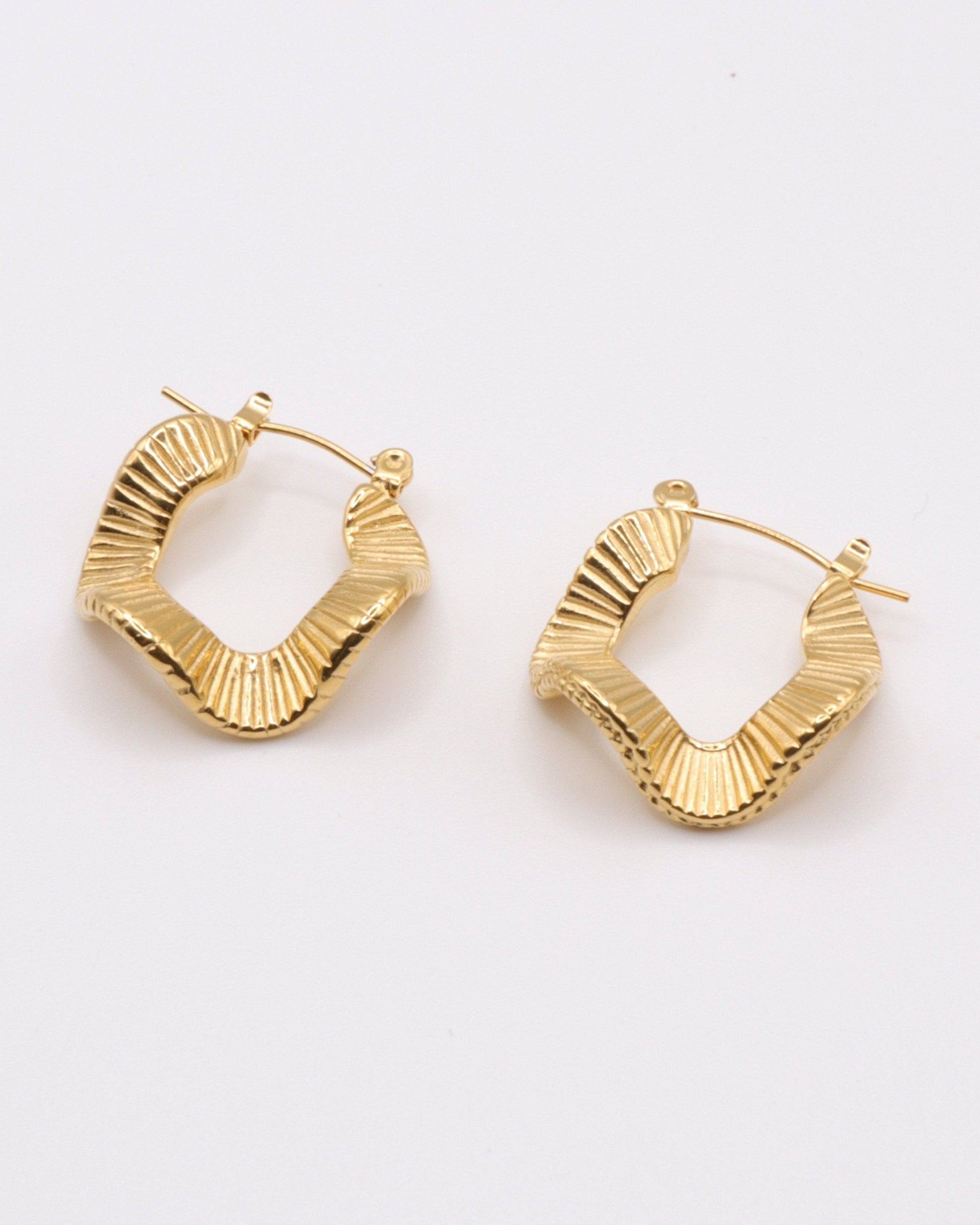photo des boucles d'oreilles créoles ondulées en doré à l'or 750/1000èeme (18 carats) sur fond gris clair