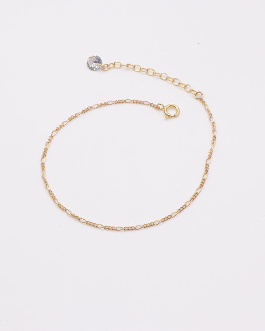 Photo du bracelet figaro et zirconium en acier inoxydable doré à l'or 750/1000ème (18 carats) sur fond gris clair