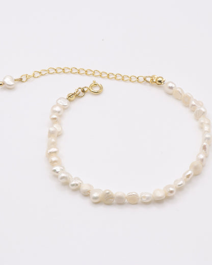 Photo du bracelet à petite perles d'eau douce doré à l'or 750/1000ème (18 carats) sur fond gris clair
