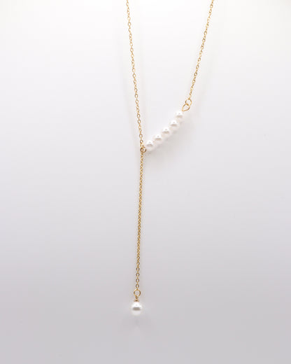 photo collier y perles doré fond gris 